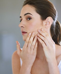 Woman checking her skin in a mirror